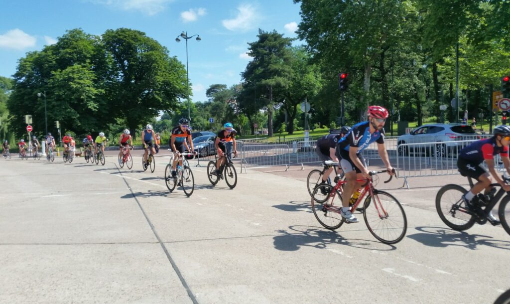 Des cyclistes qui roulent au soleil sur l'anneau de Longchamp autour de l'hippodrome