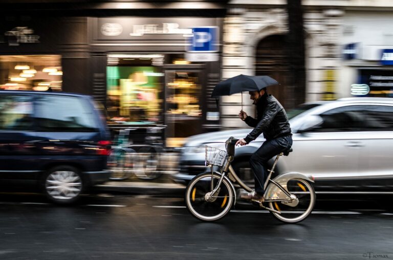 Un cycliste en vélib se protège de la pluie avec son parapluie