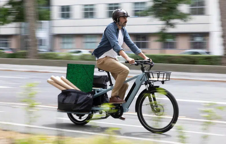 Un clycliste avec le longtail de Décathlon avec du matériel à l'arrière