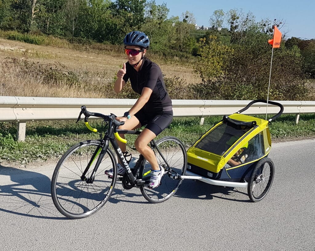 Ma femme avec son vélo de route qui tire la remorque avec le bébé