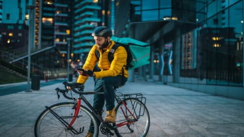 Un livreur à vélo qui attend une commande sur son smartphone