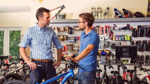 Un vendeur de vélo qui discute avec un client devant un vélo bleu