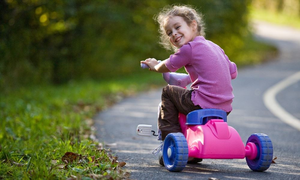 Une petite fille avec un tricycle dans la rue