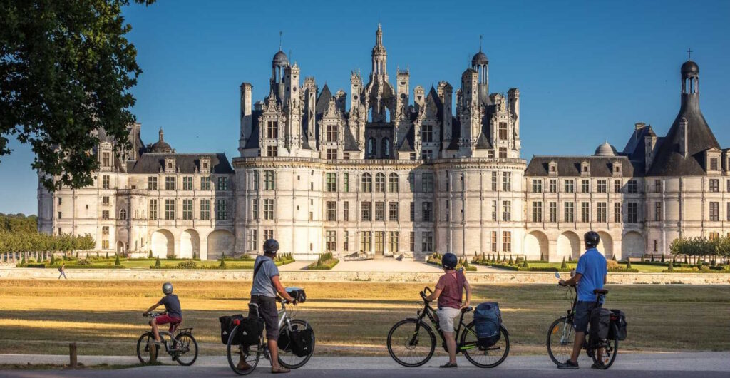 Une famille de 4 cyclistes devant un château de la Loire à vélo