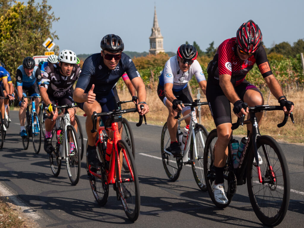 Cycliste dans le peloton qui fait un pouce en l'air