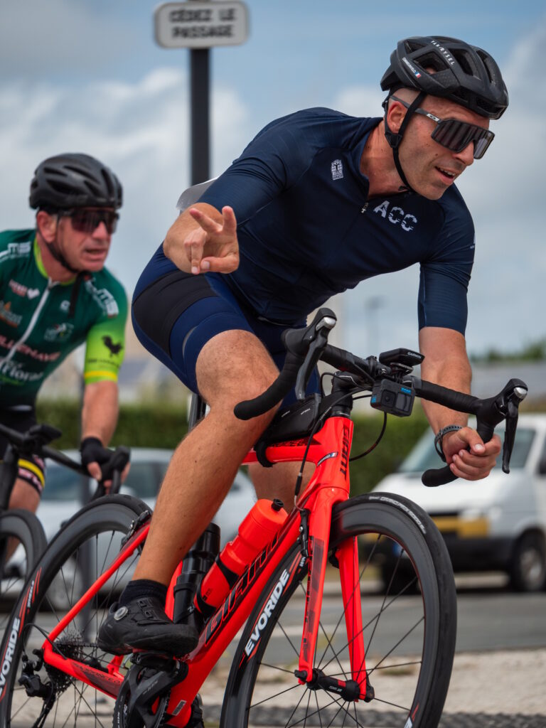 Cycliste sur un vélo rouge qui fait un signe de la main au photographe