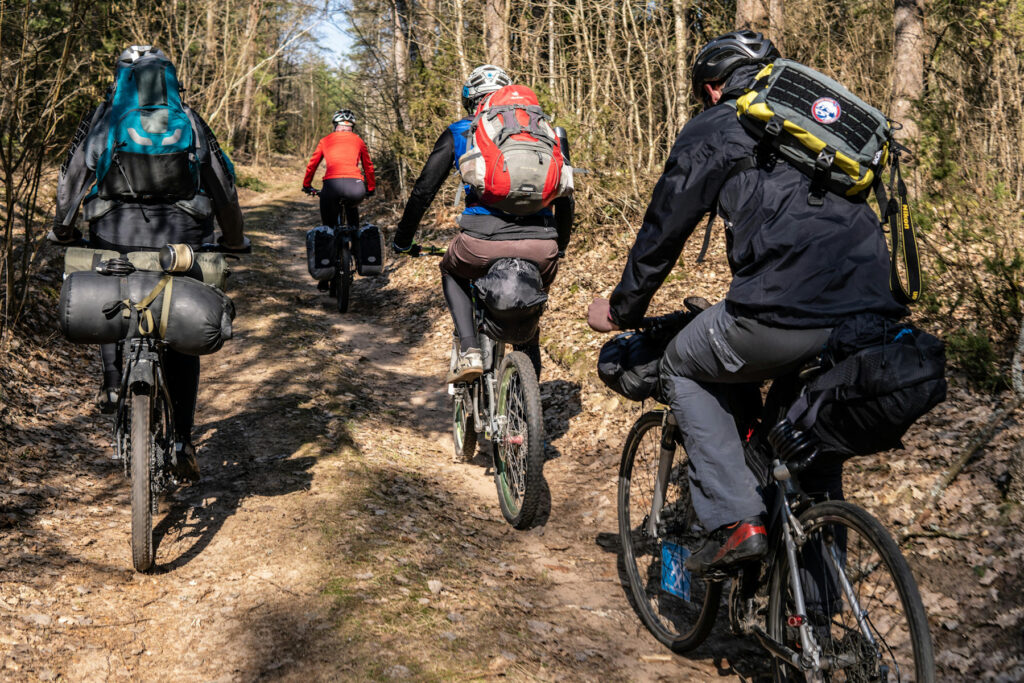 Un groupe de 4 cyclistes en bikepacking dans un chemin forestier